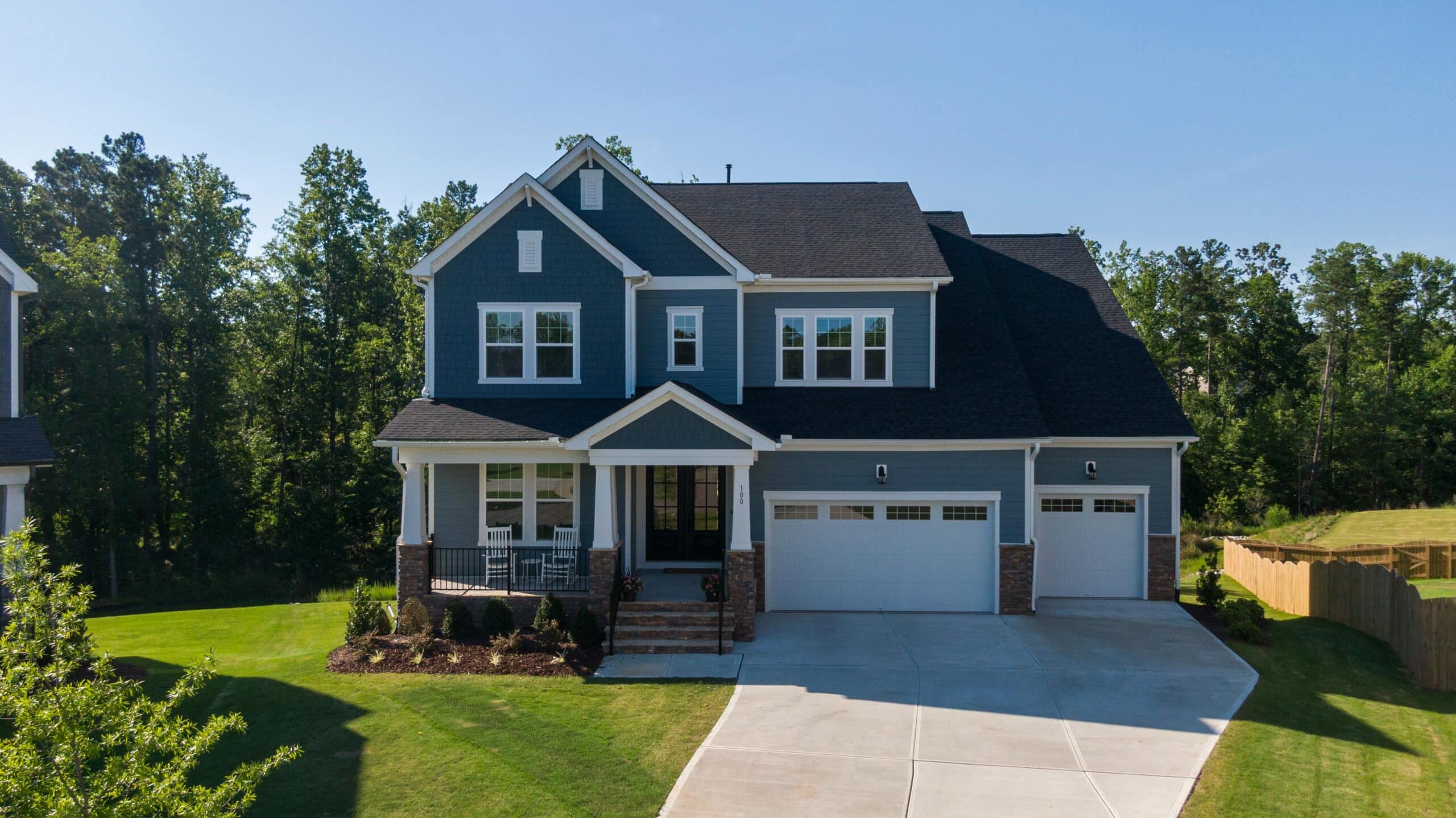 Two-story blue house with white trim, a two-car garage, and a well-manicured lawn. The house's exterior is clean, relating to the blog post "How Often Should I Wash My House for the Best Results Year-Round.